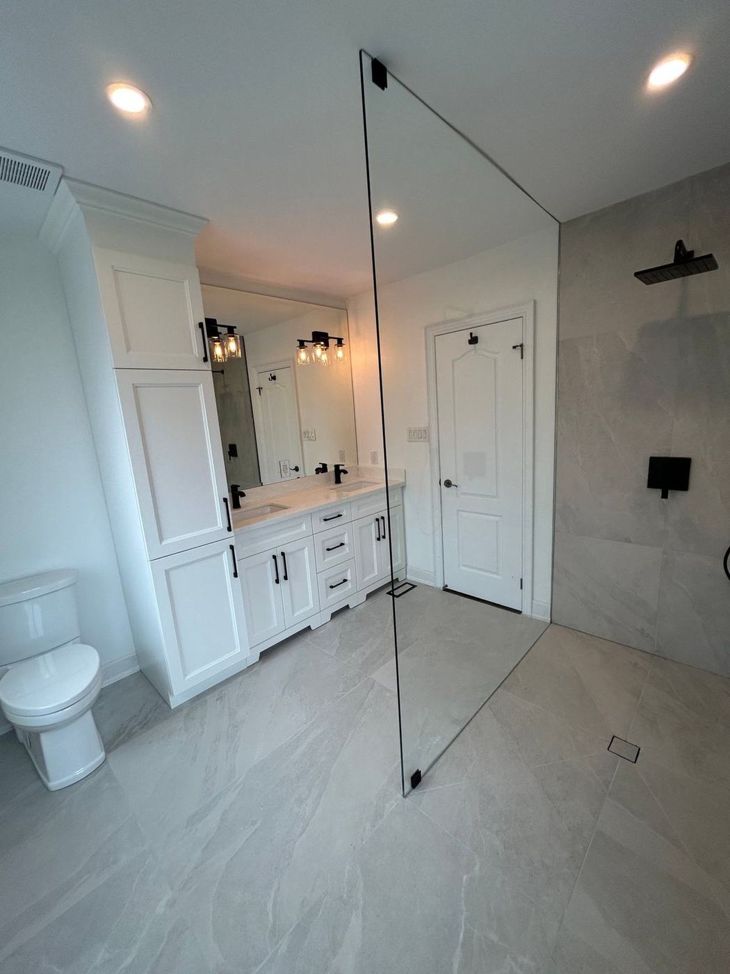 Curbless walk-in shower with a frameless glass panel and large stone-look tile in Richmond Hill, by NewGen Renovations Vaughan