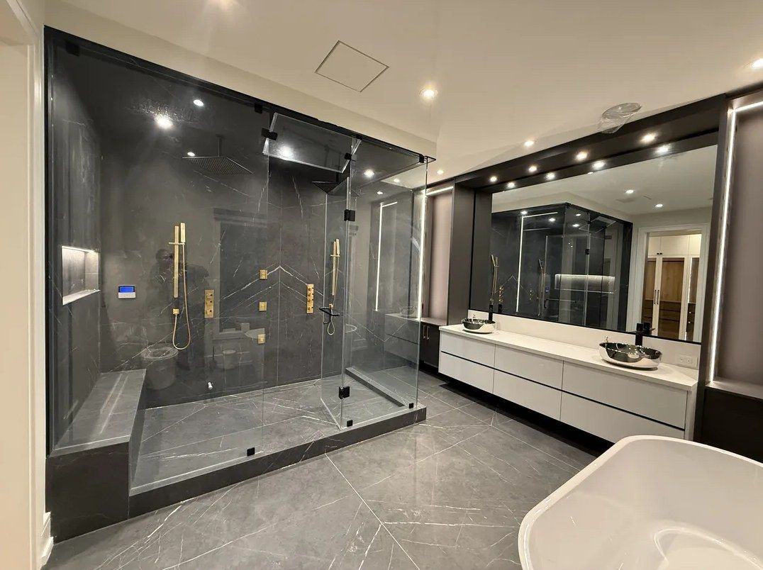 Ensuite bathroom with a glass steam shower, brushed gold fixtures, floating double vanity with a lit mirror and a freestanding tub, renovated by NewGen Renovations Vaughan