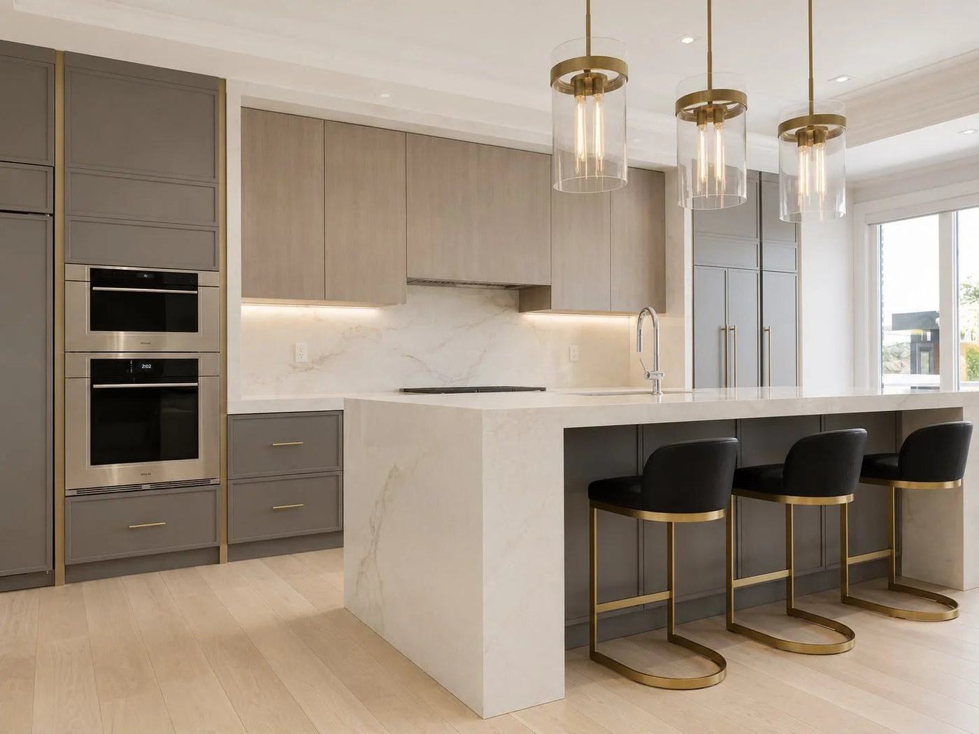 Grey and oak kitchen with a white waterfall island, glass pendants and gold-trim stools in Concord, by NewGen Renovations Vaughan