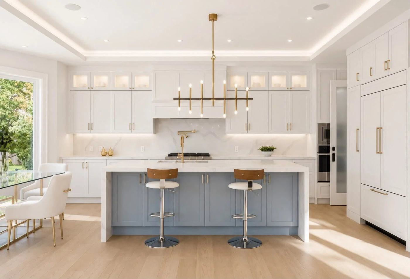 White kitchen with a blue island, quartz waterfall countertop, brass linear chandelier and glass-front upper cabinets, renovated by NewGen Renovations Vaughan